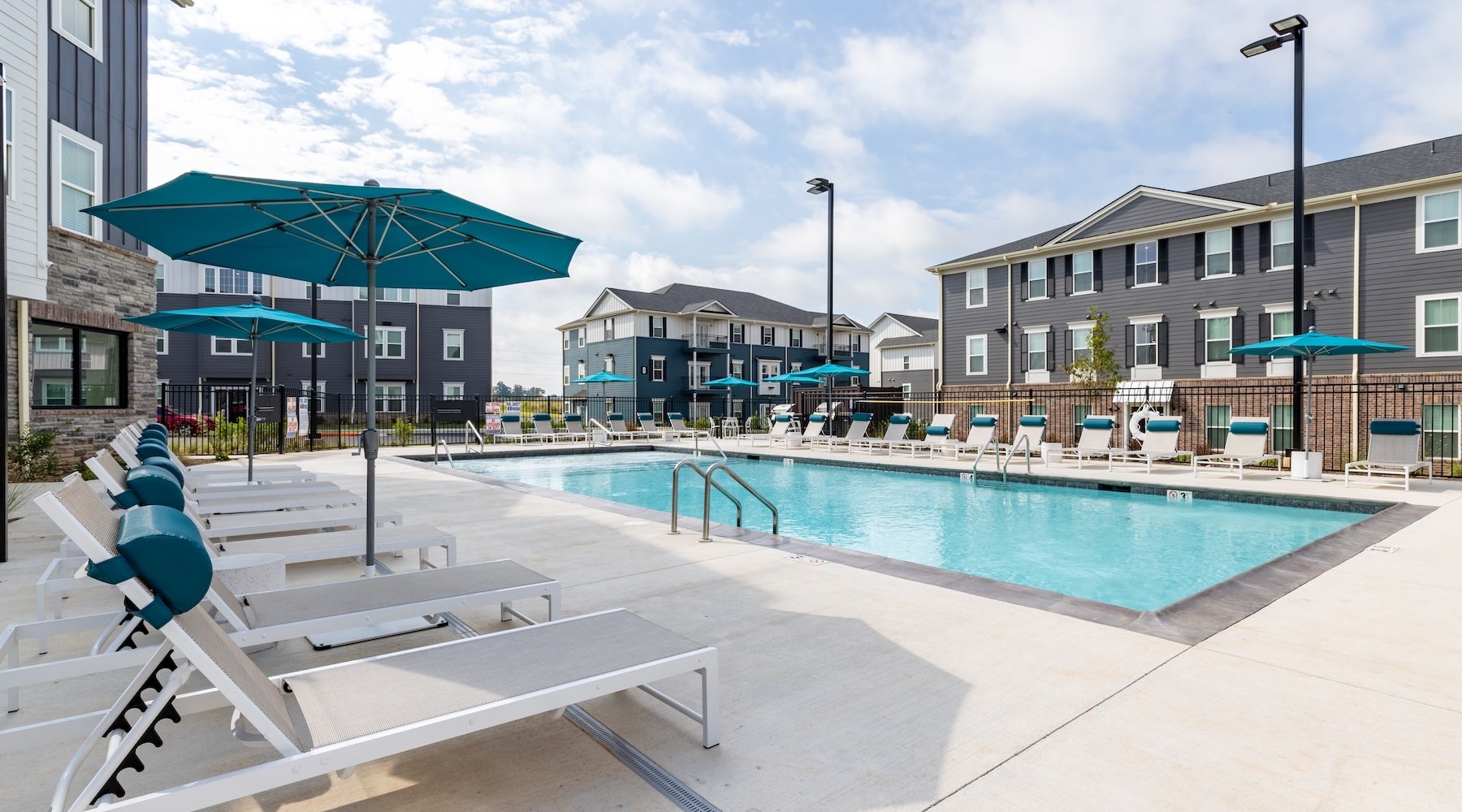 resort style pool with seating with a building behind it